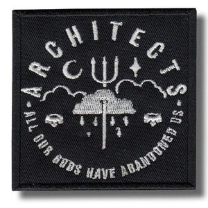 May include: Black square patch with white embroidered text and imagery. The text reads "ARCHITECTS" arched across the top, with "ALL OUR GODS HAVE ABANDONED US" along the bottom. Central design features a trident, cloud, and raindrops.