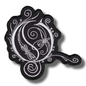 以下が含まれることがあります： 黒と白の刺繍パッチ。装飾的な文字「O」と花柄と渦巻き模様が特徴です。パッチは、湾曲した延長部を備えた独特の形状をしています。デザインは、黒い背景に白い糸で詳細に描かれています。