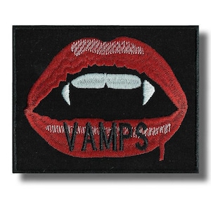Puede incluir: Parche bordado con labios rojos con colmillos blancos y la palabra "VAMPS" en rojo. El parche está sobre un fondo negro. Los labios están abiertos, revelando dientes blancos.