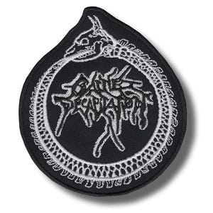 May include: Black patch with a white embroidered design featuring a skeletal dragon eating its tail, surrounding the word "DECAPITATED" in a stylized font. The patch has a teardrop shape and a white border.
