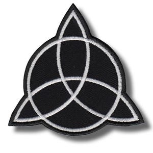 Op de afbeelding: Zwart en wit geborduurde patch met een Triquetra-symbool, een Keltisch knoopontwerp. De patch heeft een zwarte achtergrond met witte stiksels die het symbool en de vorm van de patch omlijnen. De patch is driehoekig met afgeronde randen.