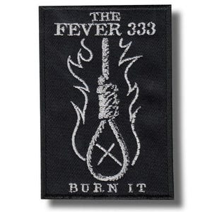 Puede incluir: Parche rectangular negro con texto e imágenes bordadas en blanco. El texto dice "THE FEVER 333" encima de un diseño de soga con llamas y las palabras "BURN IT" debajo. El parche es probablemente para ropa o accesorios.