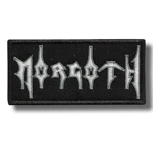 May include: A rectangular black patch with the word "MOROTH" embroidered in silver thread. The lettering has a gothic, stylized design. The patch is likely for clothing or accessories, and has a black border.