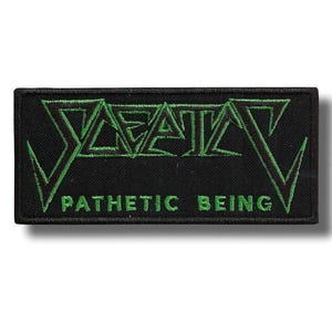 May include: Black rectangular patch with green embroidered text. The top text reads "DEATH" in a stylized font, and the bottom text reads "PATHETIC BEING". The patch has a black border and a white background.