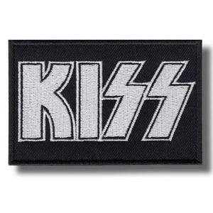May include: Black rectangular patch featuring the word "KISS" in white, embroidered block letters. The patch has a black border and is designed to be attached to clothing or accessories, possibly by ironing or sewing.