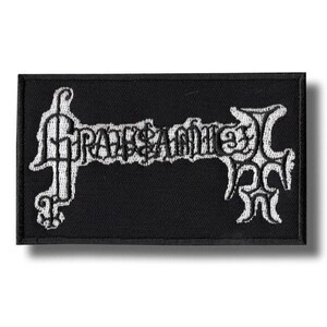 Può includere: Toppa rettangolare nera con testo ricamato bianco "GRAVESAMME". Il testo è in un carattere gotico stilizzato. La toppa ha un bordo bianco ed è probabilmente in tessuto.