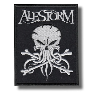 Könnte beinhalten: Schwarzer rechteckiger Aufnäher mit dem Wort "ALESTORM" in weißer, stilisierter Schrift. Darunter ein weißer Totenkopf mit Tentakeln und gekreuzten Knochen. Der Aufnäher ist wahrscheinlich für eine Band oder verwandte Merchandise-Artikel.