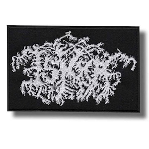 May include: Black rectangular patch with a white, intricate, abstract design. The design appears to be embroidered and has a textured appearance. The patch is likely for clothing or accessories.