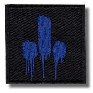 Puede incluir: Un parche cuadrado negro con un diseño abstracto azul. El diseño presenta tres formas azules con efectos de pintura goteando. El parche tiene un borde negro y es probablemente un artículo bordado o tejido.