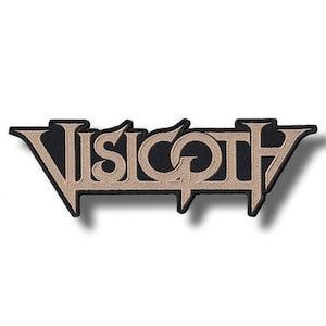 May include: A black patch with the word "VISIGOTH" embroidered in tan thread. The text is in a stylized font with a black border. The patch has a unique shape, with pointed ends.