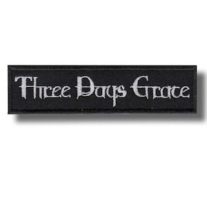 以下が含まれることがあります： 黒い長方形のパッチ。白いゴシック様式の文字で「Three Days Grace」と刺繍されています。パッチには黒い縁取りがあり、衣服やアクセサリーに縫い付けるように設計されています。