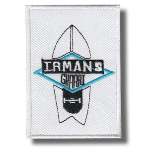 May include: White rectangular patch with a black and teal graphic design. The patch features the text "IRMANS GHOBAL" in a black font, set within a teal diamond shape. The design includes a stylized shape resembling a surfboard.