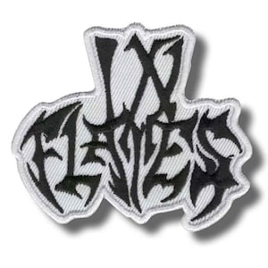May include: Embroidered patch featuring the text "IX LIVES" in a black, gothic font. The patch has a white background and a white border. The design is a stylized, decorative emblem.