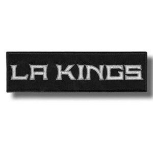 May include: Black rectangular patch with the embroidered text "LA KINGS" in white. The letters are in a stylized font. The patch is likely for a sports team.
