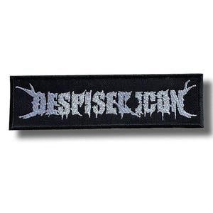 Puede incluir: Parche rectangular negro con la palabra "DESPISEICON" bordada en plata con una fuente estilizada y goteante. El parche tiene un fondo oscuro y probablemente está diseñado para aplicarse en ropa o accesorios.