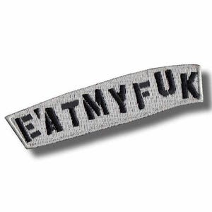 May include: A curved, rectangular patch with the embroidered text "EATMYFUK" in black capital letters. The patch has a white background and a black border.