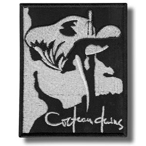 Peut inclure: Écusson brodé noir et blanc avec un motif de crâne stylisé. Le texte "Cocteau Twins" est brodé en blanc. L'écusson a une bordure noire et est destiné à être appliqué sur des vêtements ou des accessoires.