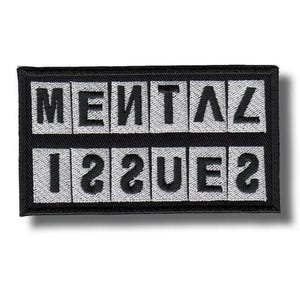 Op de afbeelding: Zwart en wit geborduurde patch met de woorden "MENTAL ISSUES". De tekst is in een vet, blokkerig lettertype, met de letters in wit tegen een zwarte achtergrond. De patch heeft een zwarte rand.