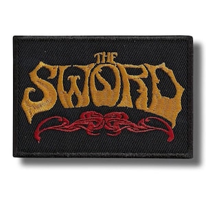 Könnte beinhalten: Schwarzer rechteckiger Aufnäher mit dem Schriftzug "THE SWORD" in goldfarbenen, stilisierten Buchstaben. Darunter befindet sich ein rotes Zierdesign. Der Aufnäher ist wahrscheinlich für eine Jacke oder eine Tasche.