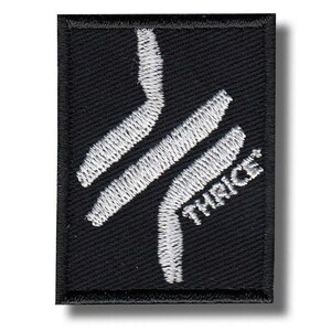 May include: Black rectangular patch with white embroidered design and the word "THRICE". The design features two parallel, curved lines. The patch is likely for clothing or accessories.