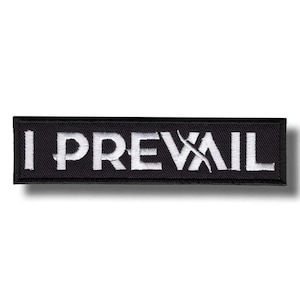 Puede incluir: Parche rectangular negro con el texto bordado en blanco "I PREVAIL". El parche tiene un borde blanco y un efecto de sombra. El parche es probablemente para ropa o accesorios.