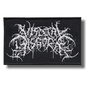 May include: Black rectangular patch with white embroidered text. The text is stylized and appears to be a band logo. The patch has a black border and is likely made of fabric.