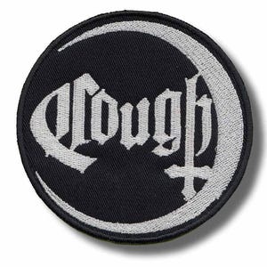 May include: A round black patch with the word "Cough" in white gothic lettering, encircled by a white crescent moon design. A white cross is below the word. The patch has a black border.