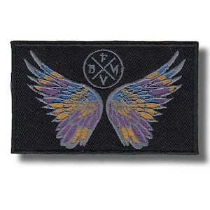 Könnte beinhalten: Schwarzer rechteckiger Aufnäher mit einem Design aus stilisierten Flügeln in Lila, Blau und Gold. Ein kreisförmiges Emblem mit den Buchstaben "B", "F", "V" und "M" befindet sich mittig über den Flügeln. Für Kleidung oder Accessoires.