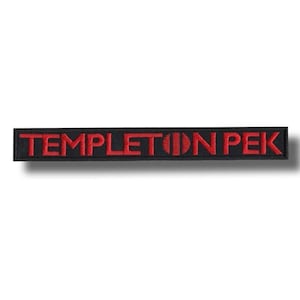 May include: A black rectangular patch featuring the embroidered words "Templeton Pek" in red. The patch is long and narrow, with the text running horizontally across the centre.