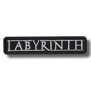 May include: Black rectangular patch with the word "LABYRINTH" embroidered in white. The patch has a black border and a white background for the letters. The patch is rectangular and has rounded corners.