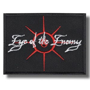 May include: Black rectangular patch featuring the embroidered text "Eye of the Enemy" in white script. A red circular design with radiating lines is centered on the patch.