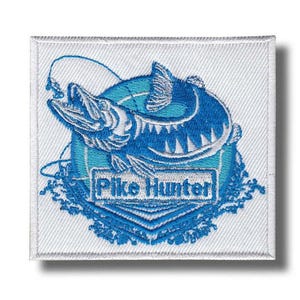 Könnte beinhalten: Quadratischer, gestickter Aufnäher mit einem blauen Hechtdesign und dem Text "Pike Hunter" in einem weißen Rechteck. Der Fisch ist von einem blauen Rand und Details der Angelschnur umgeben, vor einem weißen Hintergrund.