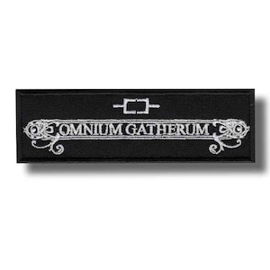 Pode incluir: Patch retangular preto com texto bordado branco e elementos decorativos. O texto diz "OMNIUM GATHERUM" em uma fonte estilizada, com um pequeno design geométrico acima. O patch tem um design limpo e minimalista.