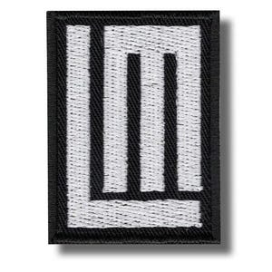 以下が含まれることがあります： 黒い縁取りと白い、様式化された「LM」デザインの刺繍パッチ。文字は太い垂直線です。パッチは長方形で、テクスチャード加工が施されています。