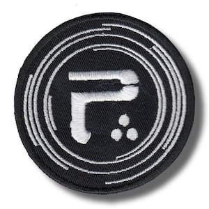 Op de afbeelding: Een ronde, zwarte geborduurde patch met een witte gestileerde letter "P" en drie stippen. De letter en stippen zijn gecentreerd binnen concentrische witte cirkels, wat een modern, grafisch ontwerp creëert. De patch heeft een strakke, minimalistische esthetiek.