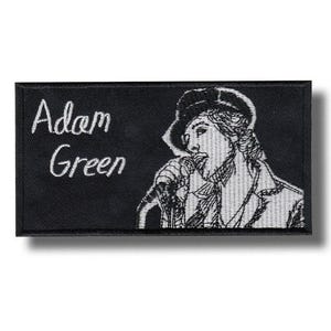 May include: Black rectangular patch featuring the name "Adam Green" in white script. A black and white illustration of a person singing into a microphone is on the right side.