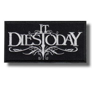 Pode incluir: Patch retangular preto com a inscrição branca bordada "IT DIES TODAY" em fonte gótica estilizada. O texto é emoldurado por enfeites decorativos. O patch tem uma borda preta.