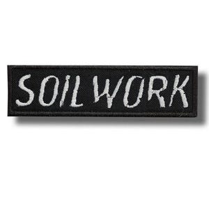 Könnte beinhalten: Schwarzer rechteckiger Aufnäher mit dem gestickten Text „SOIL WORK“ in Weiß. Der Aufnäher ist wahrscheinlich aus Stoff und hat einen Rand. Der Text ist in einem handschriftlichen Stil gehalten.