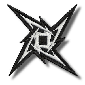 May include: Embroidered patch in black and white, featuring a starburst design. The patch has a black background with a white embroidered design. The design includes a central square and radiating lines.