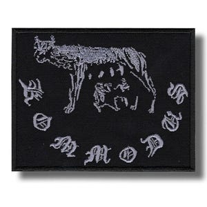 Könnte beinhalten: Ein schwarzer, bestickter Aufnäher mit einem stilisierten Wolf und zwei kleineren Figuren, möglicherweise Jungtiere, in einem Kreis aus verziertem Text. Der Wolf und der Text sind hellgrau auf schwarzem Hintergrund.