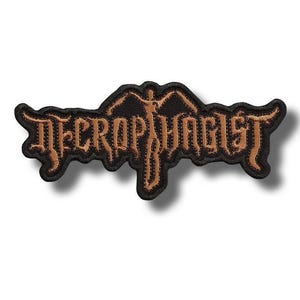 Può includere: Toppa ricamata nera e marrone con la scritta "NECROPHAGIST" in lettere stilizzate. La toppa ha un bordo decorativo e una grafica di una figura con le braccia tese. Adatta per abbigliamento o accessori.