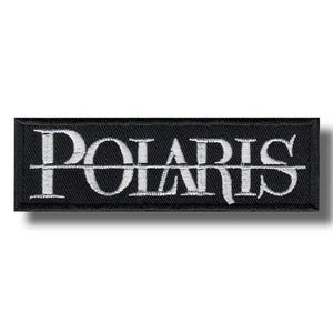Może przedstawiać: Czarna, prostokątna naszywka z haftowanym napisem "POLARIS" w białych, stylizowanych literach. Tekst jest wyśrodkowany i podzielony poziomo cienką białą linią. Naszywka ma czarną obwódkę.
