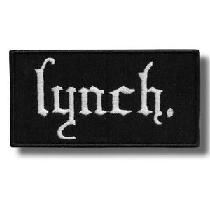 以下が含まれることがあります： 黒い長方形のパッチ。白のゴシック体で「lynch.」の文字が刺繍されています。パッチには黒い縁取りと影の効果があり、わずかに浮き上がって見えます。