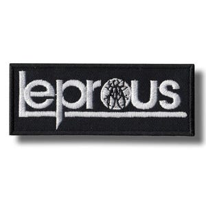 Op de afbeelding: Zwart rechthoekig embleem met het woord "LEPROUS" in wit geborduurd. Het logo van de band staat in het midden van het woord. De patch is waarschijnlijk voor een jas of tas.