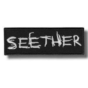 Puede incluir: Parche rectangular negro con la palabra "SEEETHER" bordada en blanco. El texto está en una fuente estilizada, ligeramente desgastada. El parche está diseñado para su aplicación en ropa o accesorios, ofreciendo una estética sencilla y audaz.