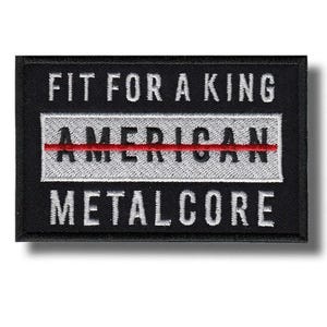 May include: Black rectangular patch with white embroidered text that reads "FIT FOR A KING" above "AMERICAN METALCORE". The word "AMERICAN" is in a white rectangle with a red line through it.