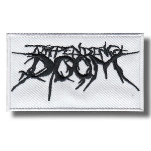 May include: A rectangular white patch with black embroidered text that reads "INDEPENDENCE DOOM" in a stylized, gothic font. The patch has a stitched border and a shadow.