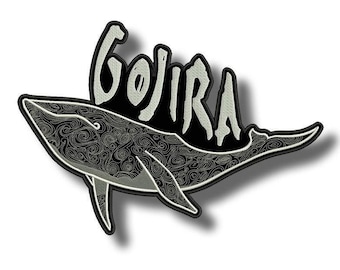 May include: Embroidered patch with a whale design in black and white, featuring detailed patterns. The word "GOJIRA" is arched above the whale in a stylized font, outlined in white. The patch has a black border.