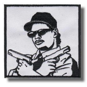 May include: Black and white embroidered patch featuring a stylized illustration of a person wearing sunglasses and a cap, holding two handguns. The patch has a square shape with a black border and a white background.
