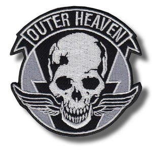 May include: Embroidered patch featuring a skull with wings and the text "OUTER HEAVEN" in a curved banner. The design includes a gray lightning bolt and a black and gray color scheme. The patch is circular in shape.